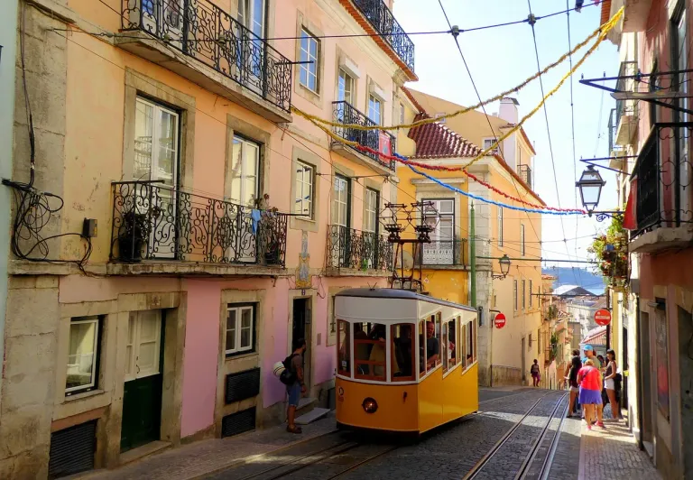 A yellow tram climbs a hill in Lisbon's Alfama & Mouraria districts.