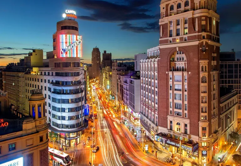 Night view of Madrid's Gran Vía, showcasing its vibrant architecture and bustling street life.