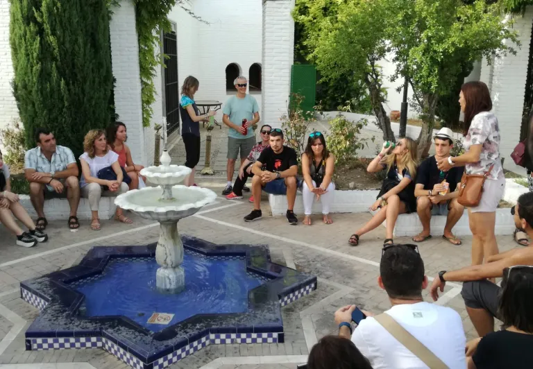A tour group listens attentively to their guide in a beautiful Seville courtyard.
