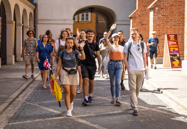 Happy tourists on a guided walking tour in Warsaw's Old Town.