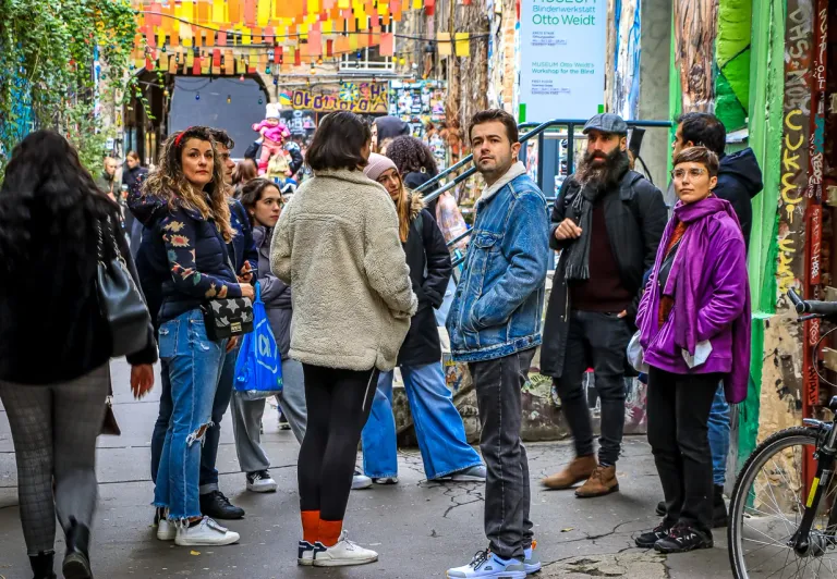 Tourists exploring a vibrant Berlin street art alley.