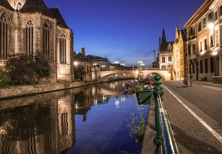 Ghent's charming canal at night, reflecting historic buildings.