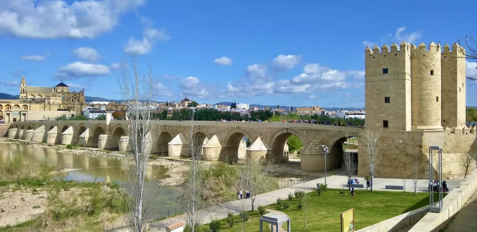 Roman Bridge over Guadalquivir River in Cordoba, with Calahorra Tower and Mezquita-Cathedral in the background under a blue s