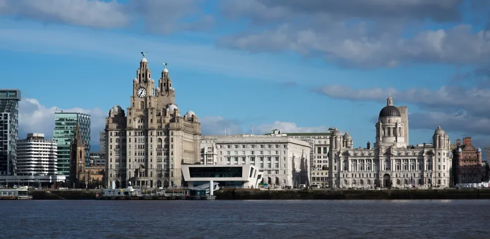 Liverpool waterfront with the Royal Liver Building, Cunard Building, and Port of Liverpool Building under a partly cloudy sky