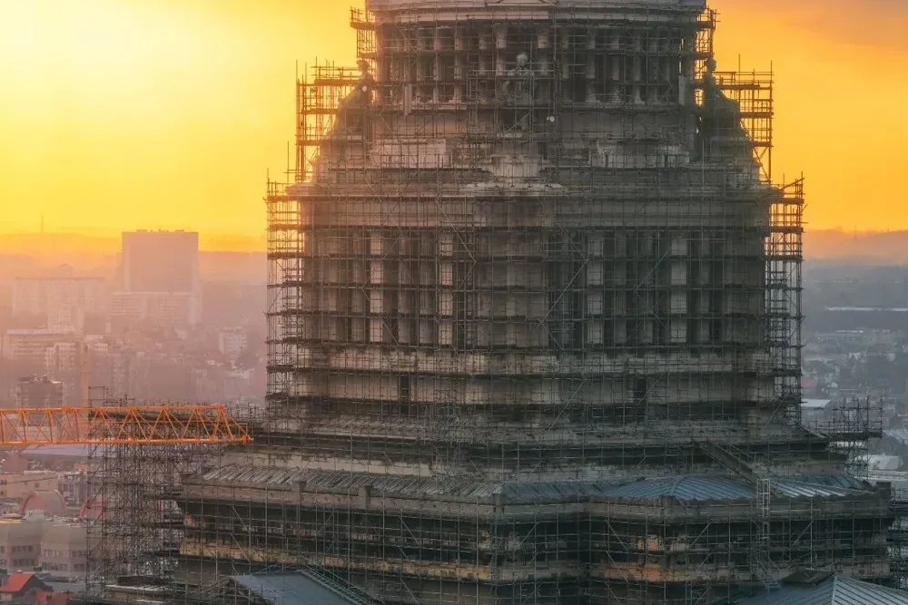 The Palace of Justice in Brussels, a large historic building, mostly covered in dark scaffolding at sunset. A golden dome ...