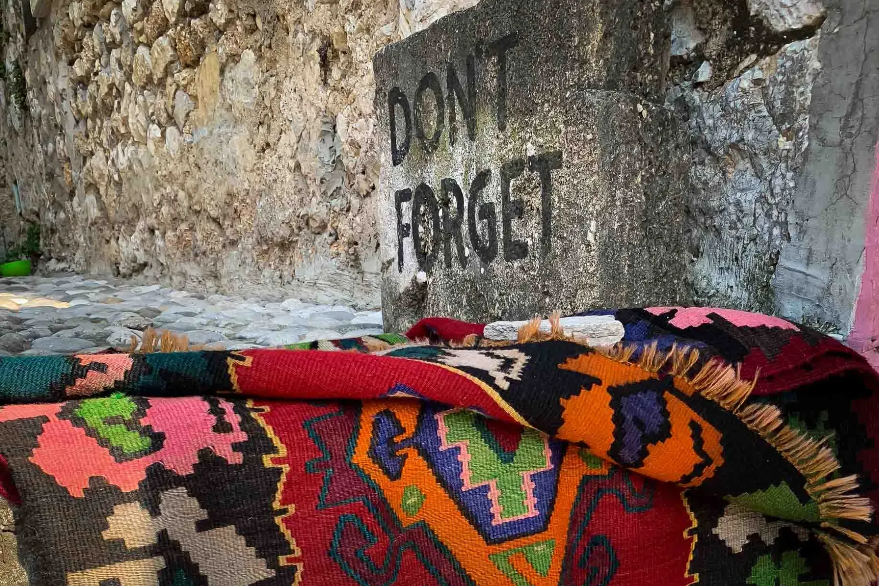 Colorful rug in Berat, Albania near a stone wall.
