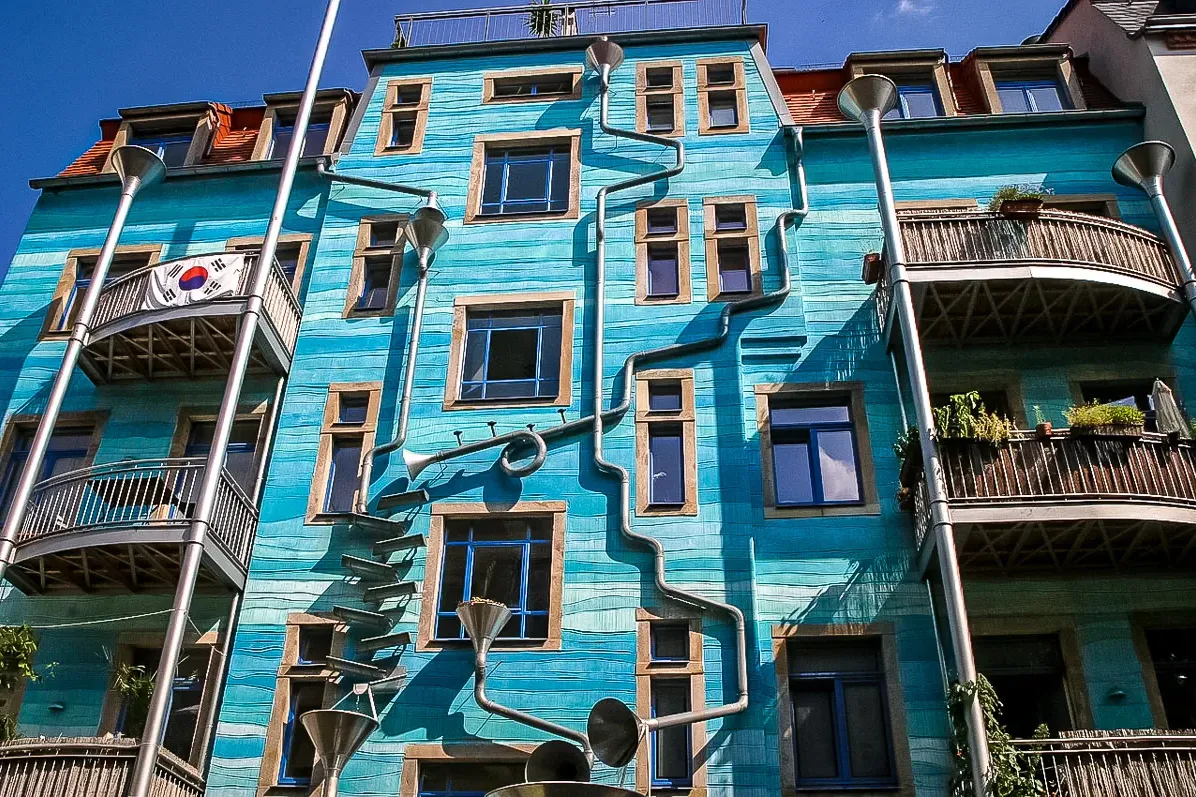 Blue building facade in Dresden with artistic downspouts and funnels, resembling musical instruments. A South Korean flag ...