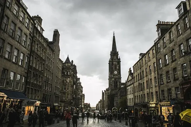 Street scene in Edinburgh's Old Town, with historic stone buildings lining a cobblestone street leading to Tron Kirk with ...
