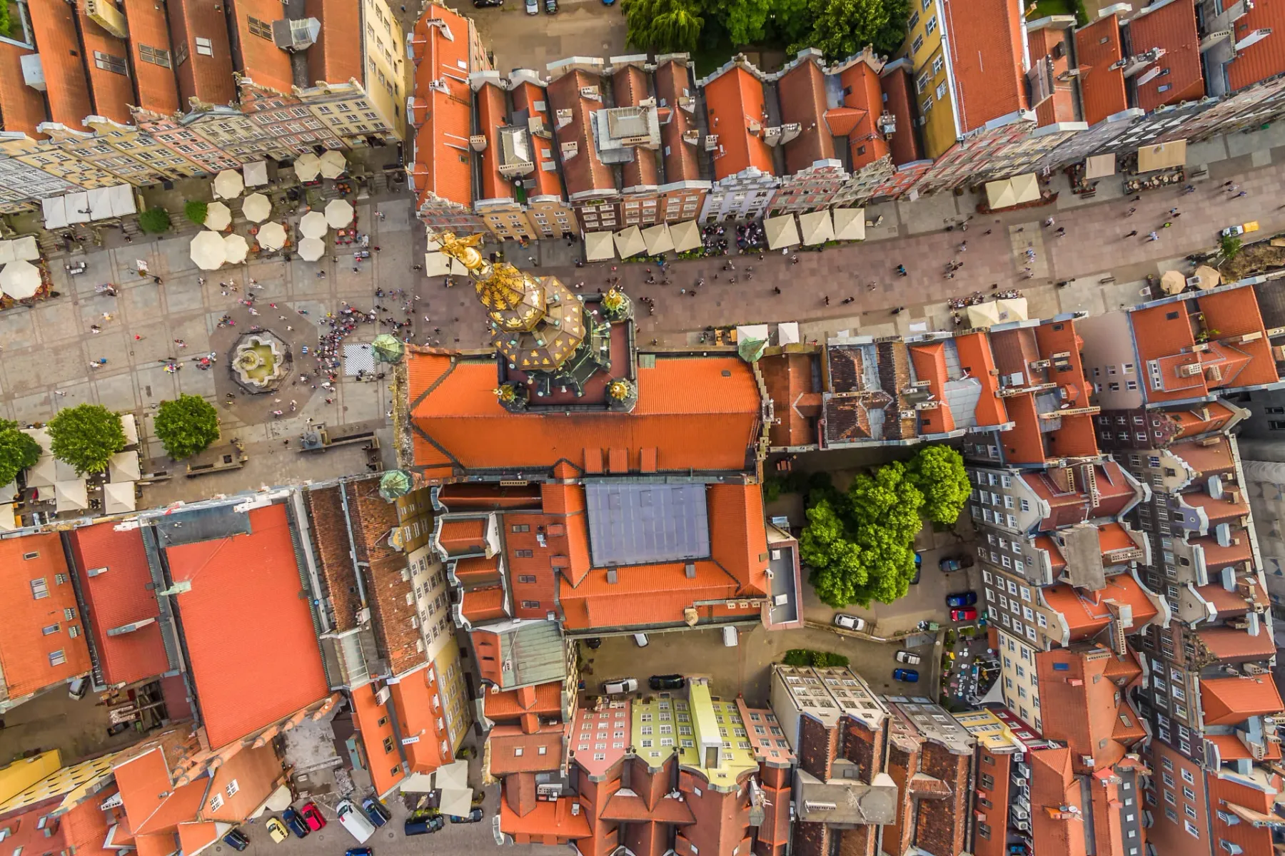 Aerial view of Gdansk's Main Town square, Dlugi Targ, with Neptune Fountain, people, and historic buildings with red roofs.