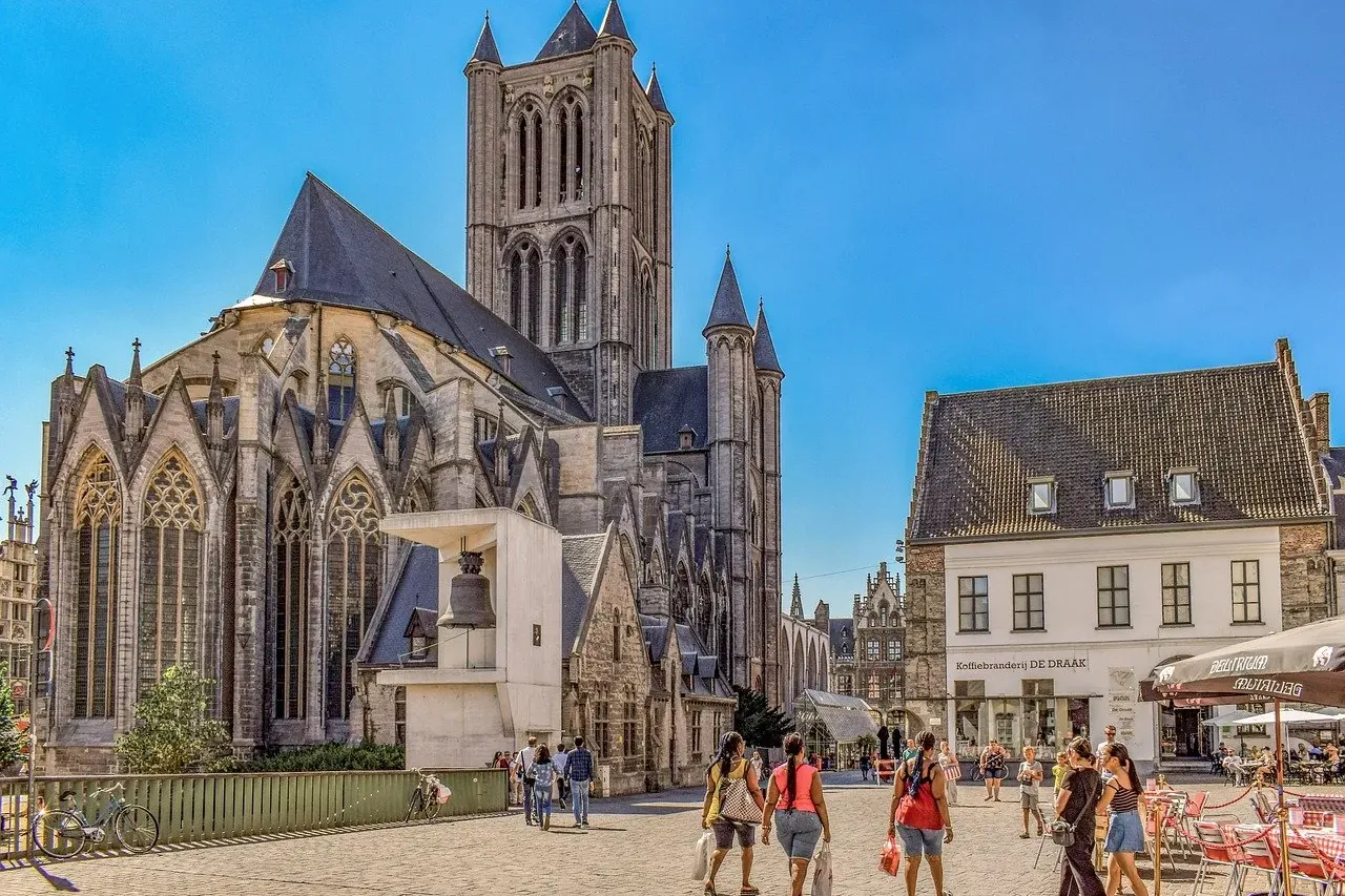 Historic St. Nicholas' Church with its tall bell tower, a traditional building, and people walking on a sunny cobblestone ...