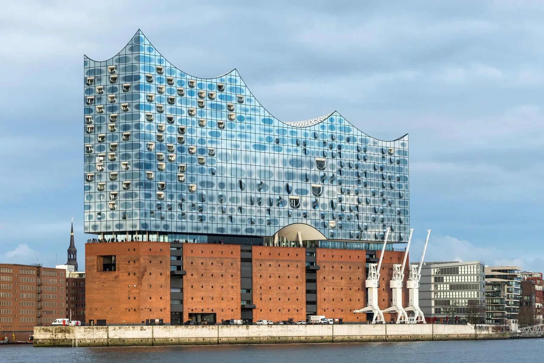 The Elbphilharmonie concert hall in Hamburg, with its glass wave-like upper structure and brick base, viewed from the Elbe...