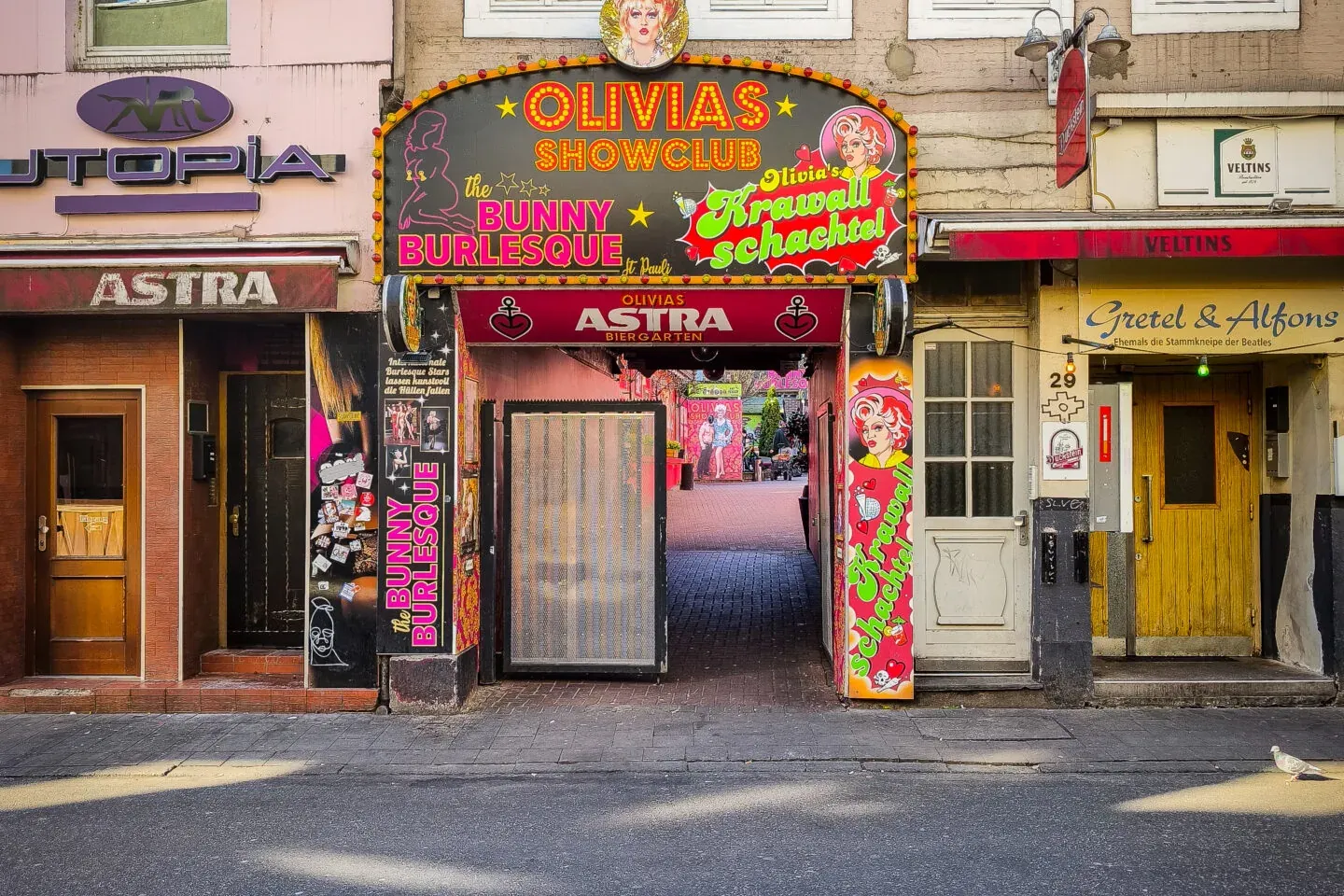 Olivia's Showclub entrance in Hamburg, featuring a bright neon sign with caricatures, flanked by Utopia and Gretel & Alfon...