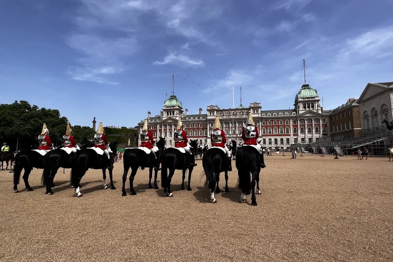 Five Household Cavalry mounted soldiers in red and white uniform on black horses, facing away, at Horse Guards Parade in L...