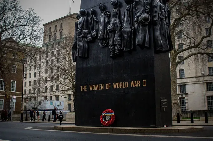 The Women of World War II Memorial in London, a large black monument with bronze figures, seen from a street view.