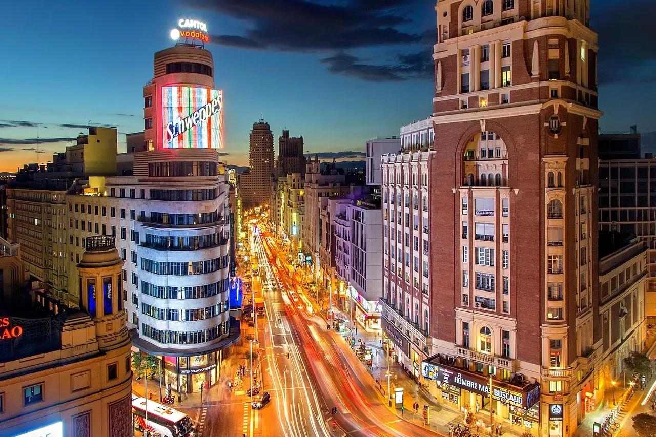 Gran Vía street in Madrid at night, with the Capitol Building's Schweppes sign and vehicle light trails.