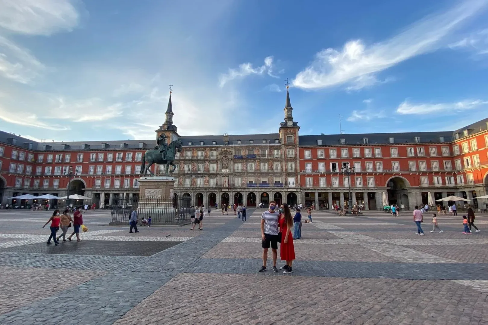 Equestrian statue of Philip III in the center of Madrid's Plaza Mayor, surrounded by red buildings with white windows unde...