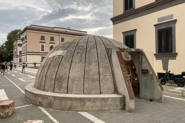 A concrete, dome-shaped former bunker building now a museum, with a glass entrance reading "MUSEUM" on a city street.