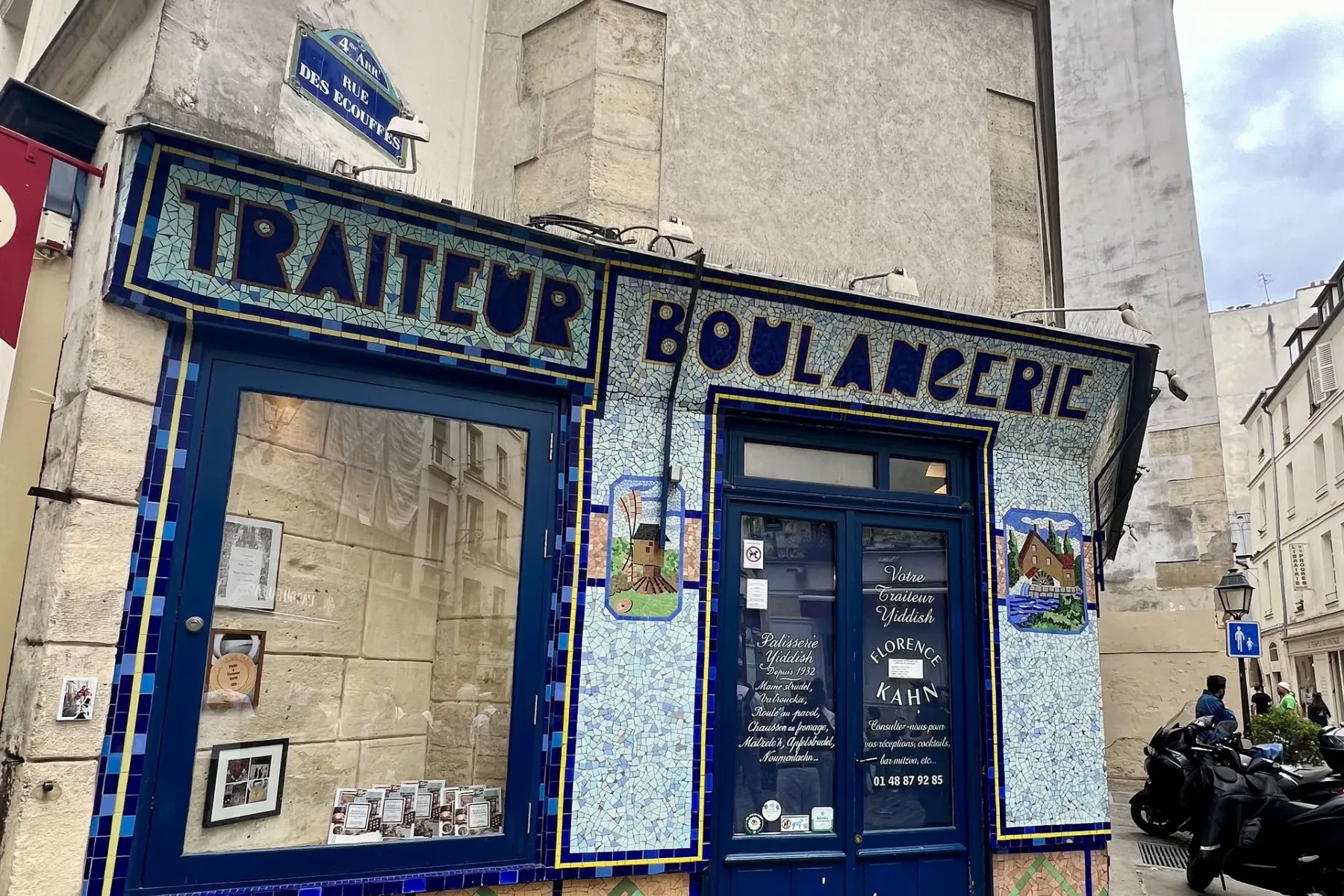 Mosaic-tiled storefront of Florence Kahn Traiteur Boulangerie on a cobblestone street in Paris, with a 'Rue des Ecouffes' ...