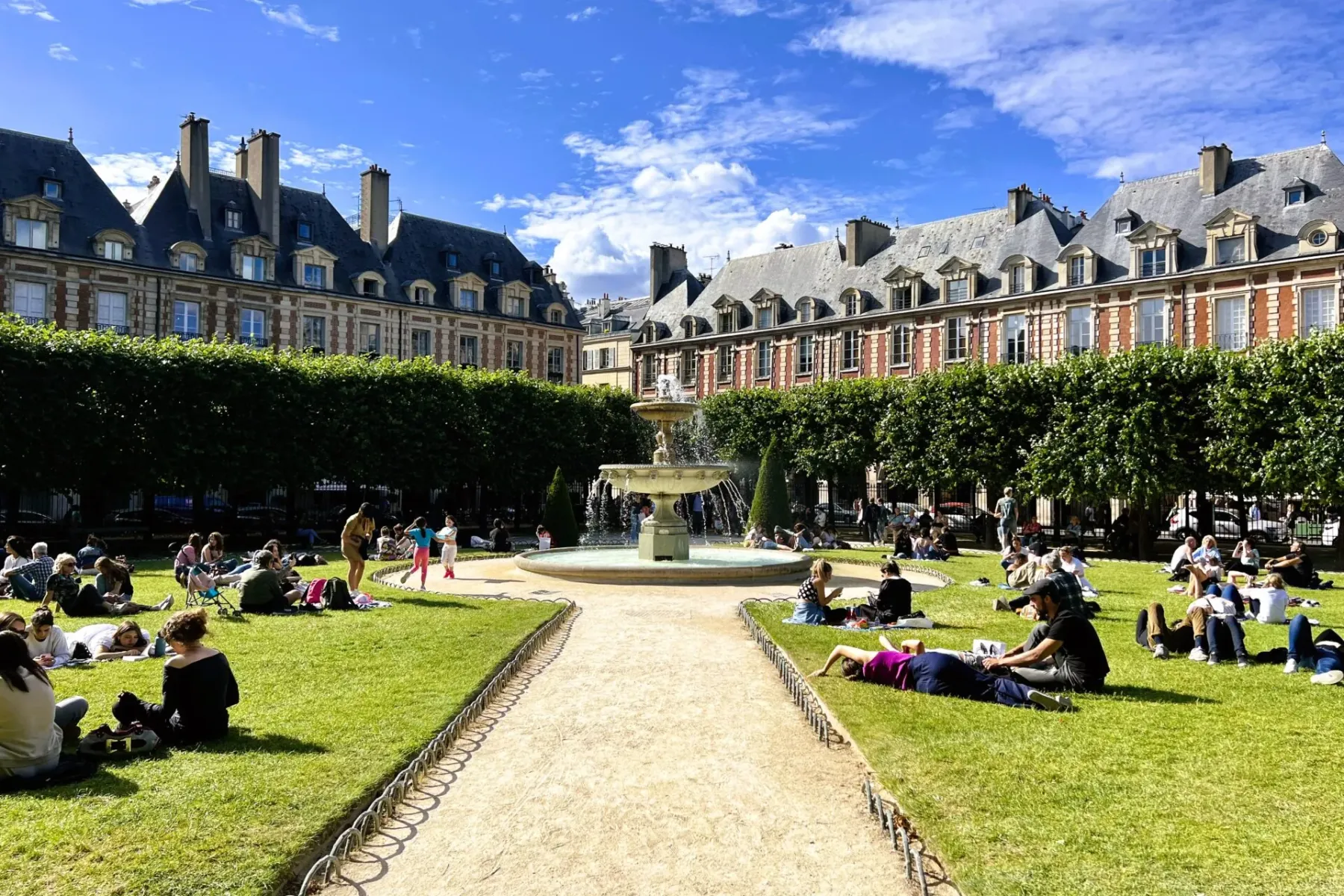 People relaxing in a sunny Parisian square.