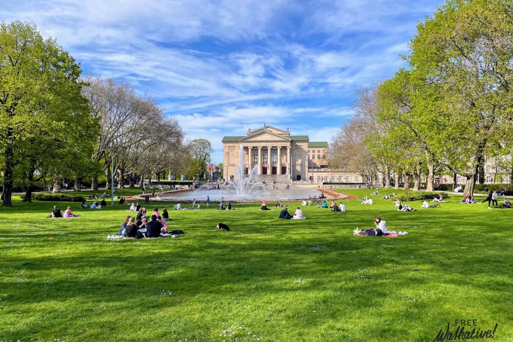 Relaxing scene in Poznań's park with the Grand Theatre in the background.