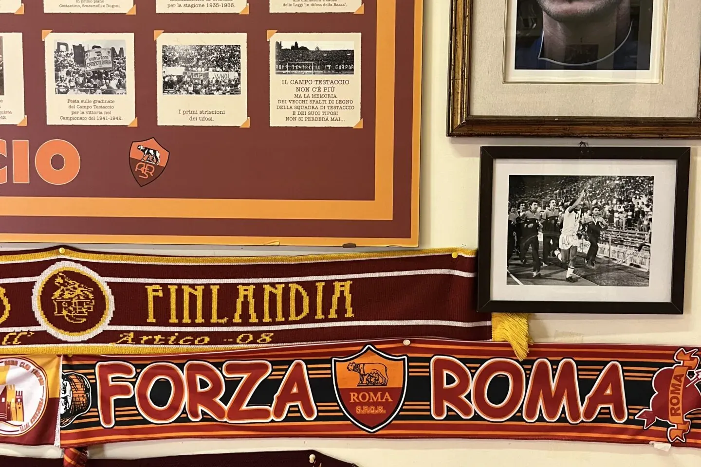 A wall display featuring AS Roma football club memorabilia: scarves, a portrait of Francesco Totti, and historical photos.