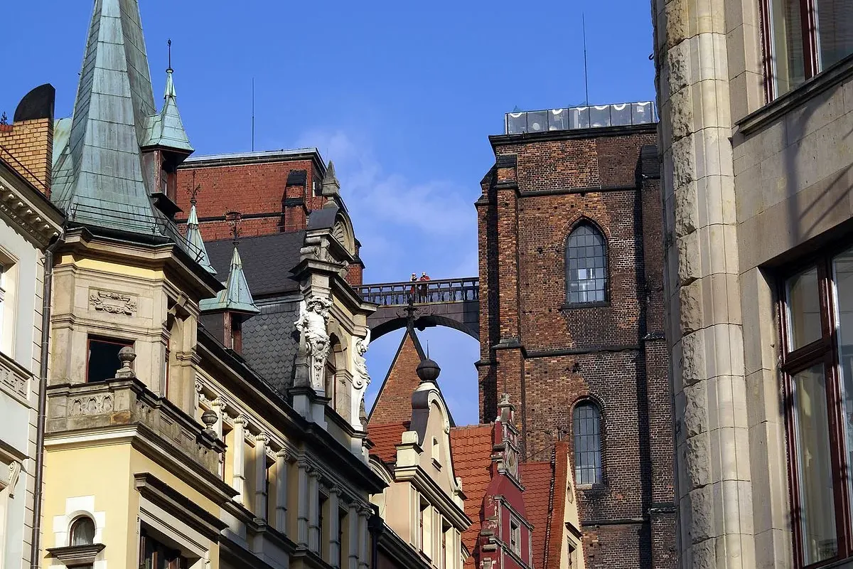 View of the Penitent Bridge connecting two brick towers, seen from a street between historic buildings with spires and dec...