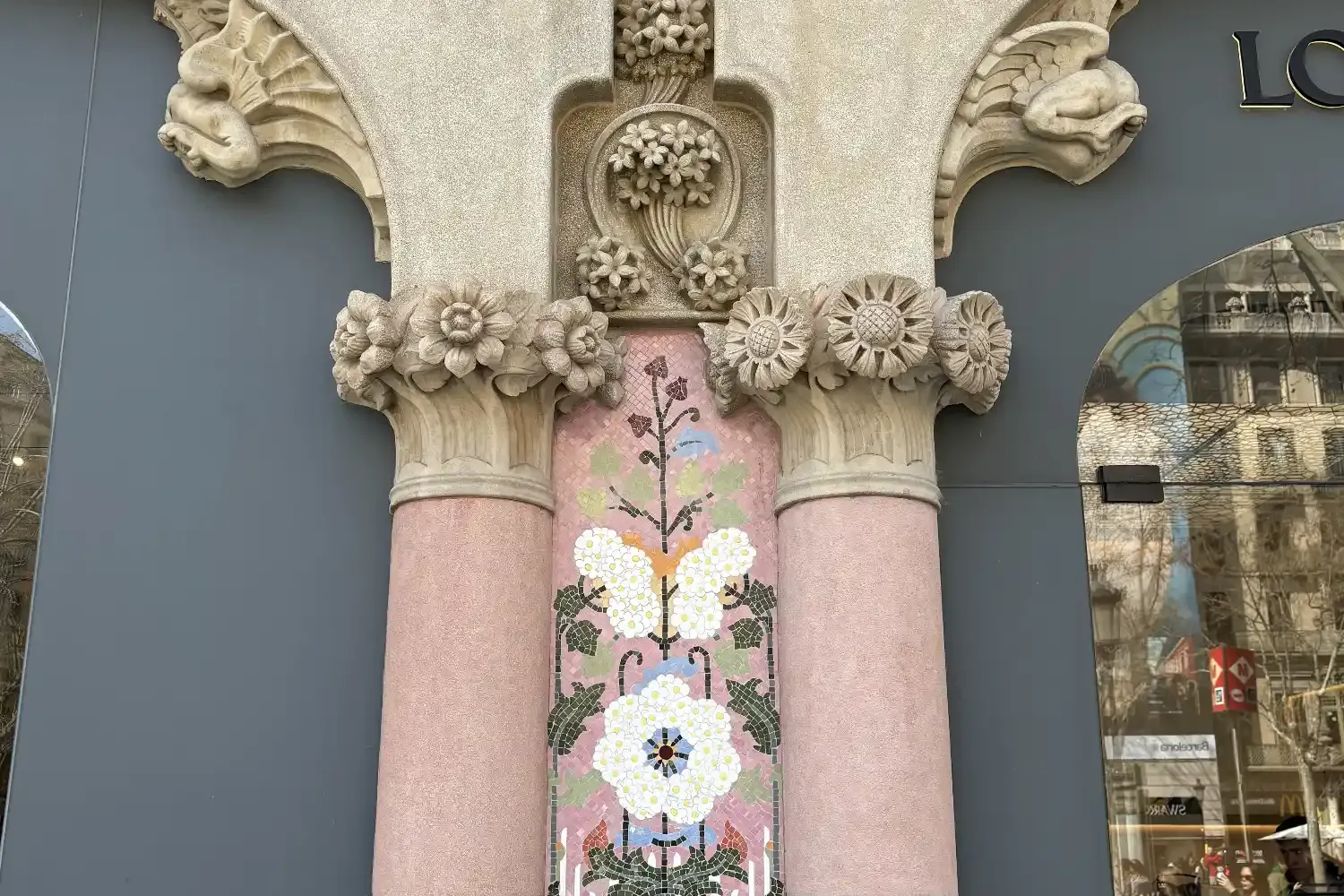 Floral mosaic and carved stone columns at Casa Lleó Morera's facade on Passeig de Gràcia, Barcelona.