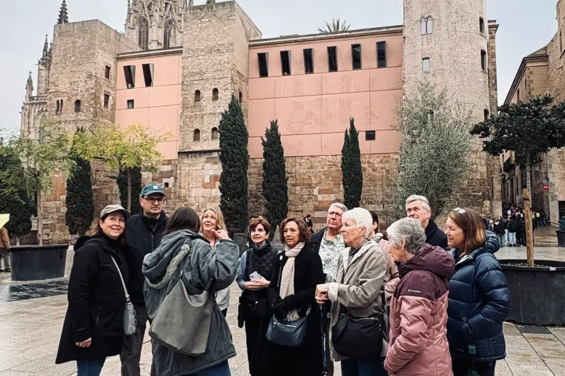 A tour guide speaking to a group of visitors in front of the Cathedral of Barcelona in the Gothic Quarter.