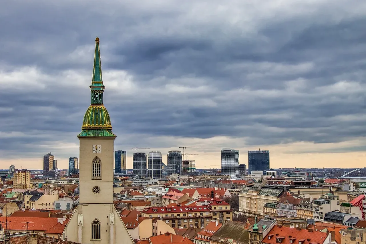 St. Martin's Cathedral tower with green spire and clock face overlooking Bratislava's old town and modern city skyline und...