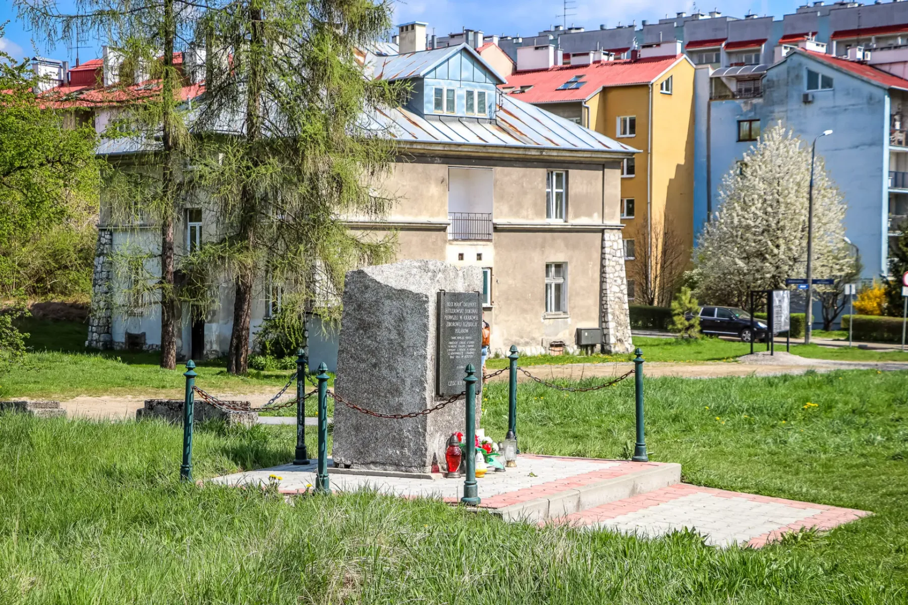 A stone memorial in a grassy area in front of the historic Grey House at the former Płaszów camp site in Krakow.
