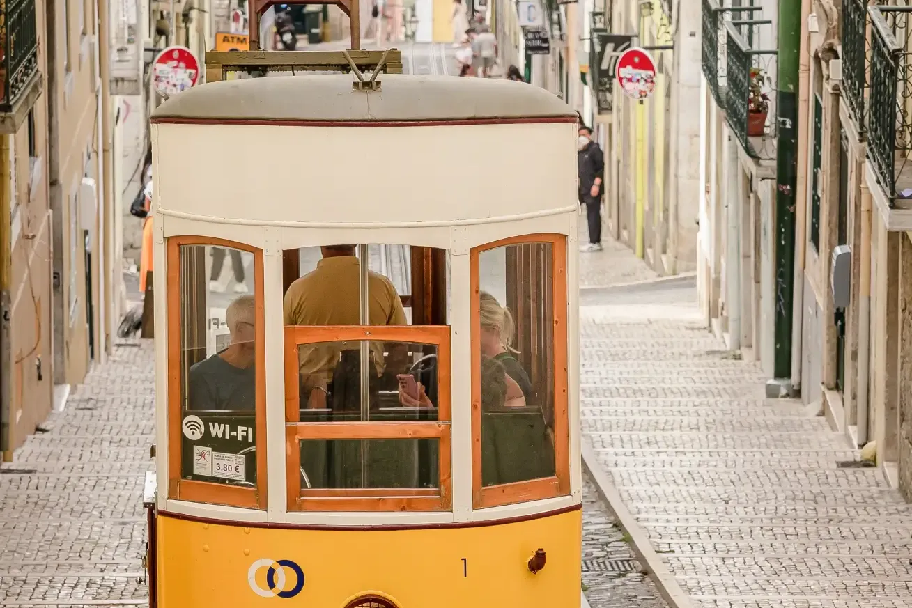 Yellow funicular tram climbing a steep cobbled street lined with historic buildings in Lisbon.