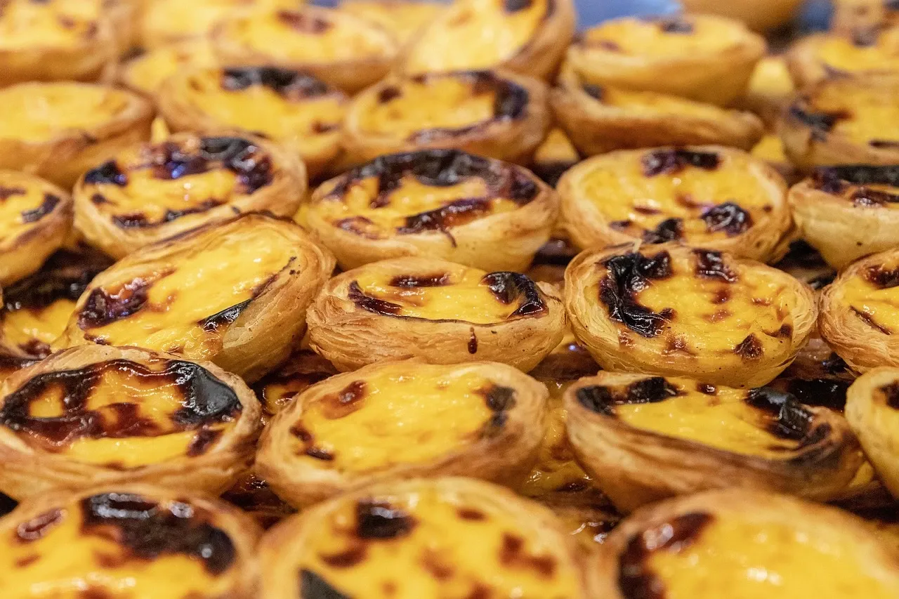 A close-up view of many Pastéis de Nata, Portuguese custard tarts with a dark, caramelized top.