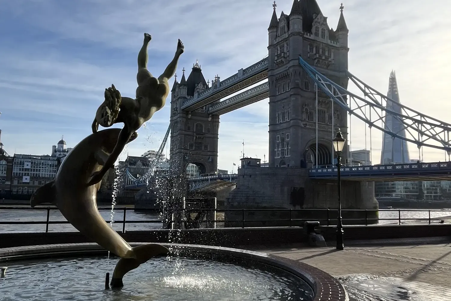The Girl with a Dolphin fountain on the bank of the Thames, with Tower Bridge and the Shard in the background.
