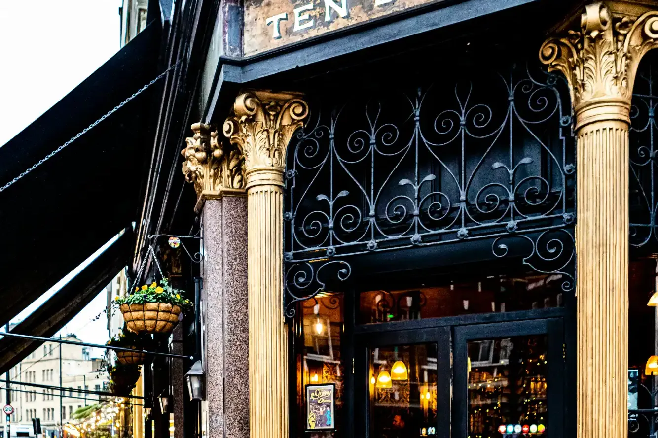 Ornate black and gold entrance to The Ten Bells pub on a London street, with its sign displayed above.