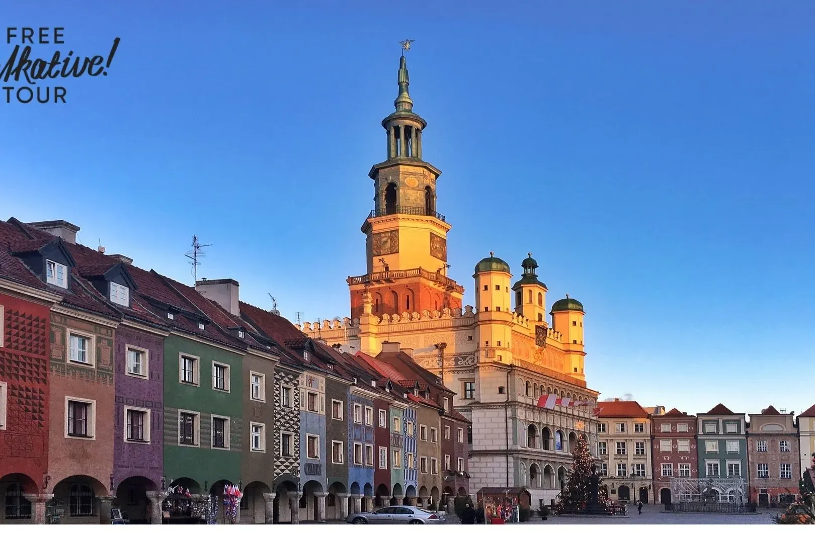 Poznań Old Town Hall with a tall clock tower, surrounded by colorful historic merchant houses under a clear blue sky.