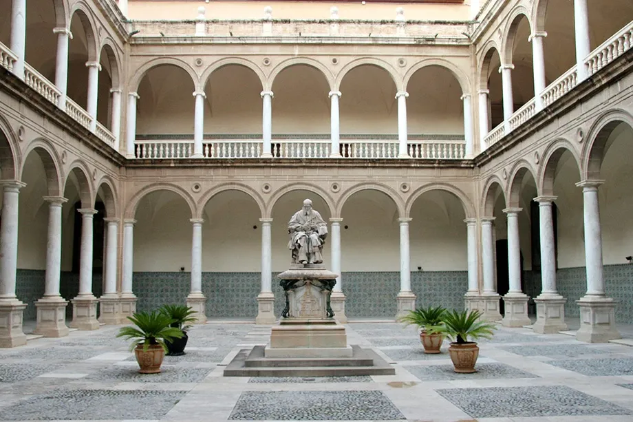 Statue in the courtyard of the Real Colegio del Patriarca in Valencia, surrounded by a two-story arched colonnade.