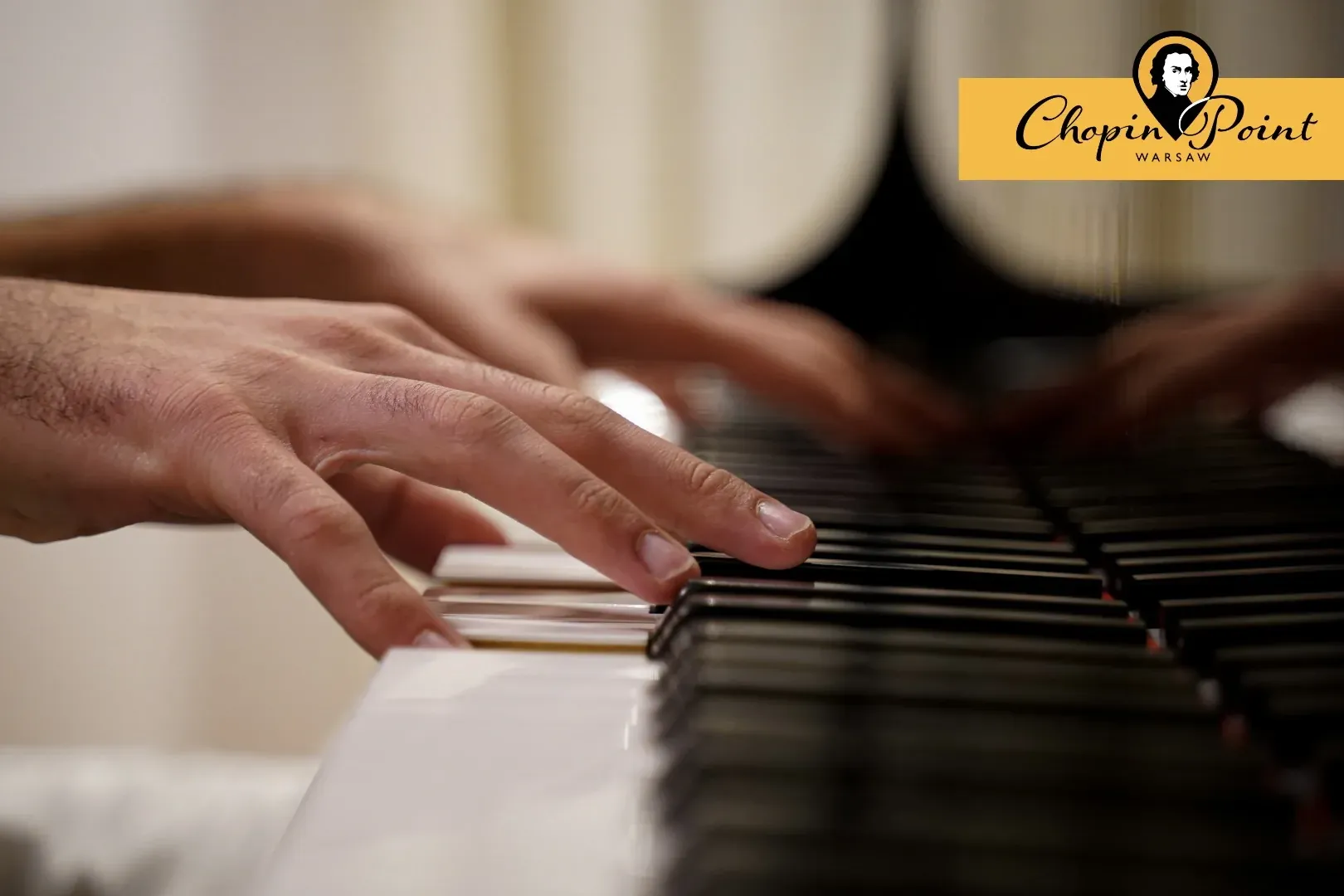 Close-up of a person's hands playing black and white piano keys during a performance.