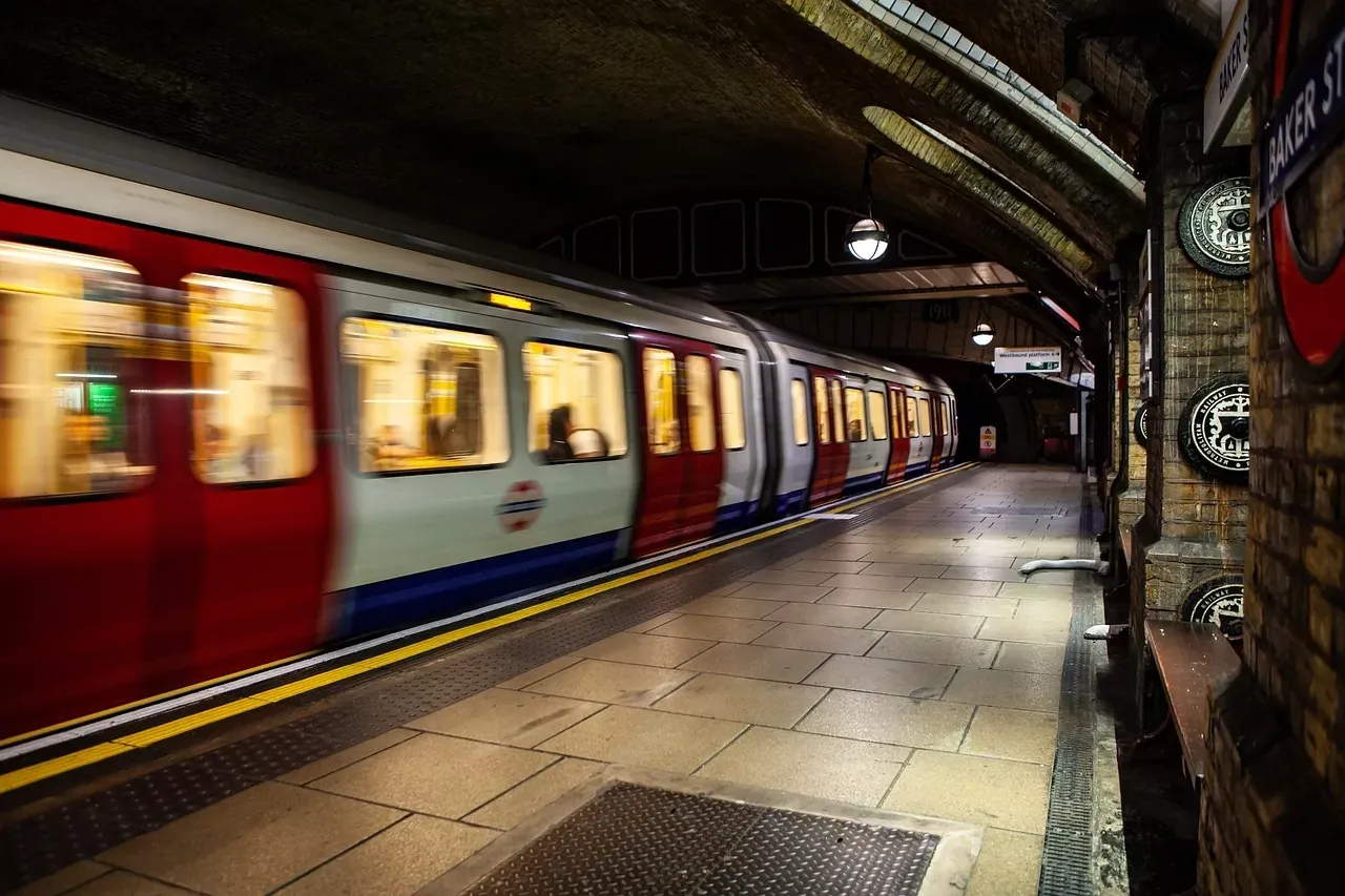 London Underground train with motion blur arriving at Baker Street station platform with brick walls and arched ceiling.