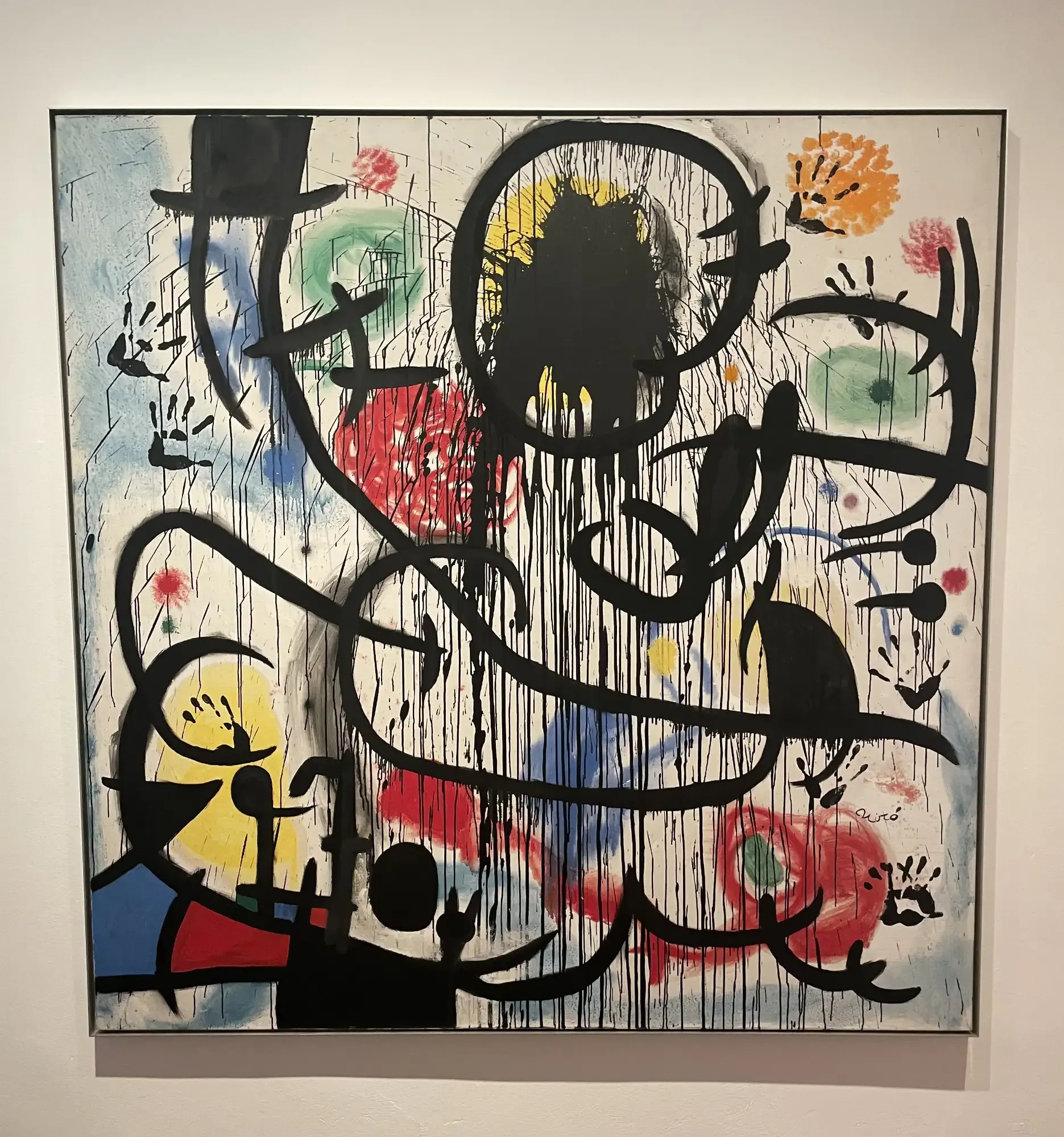 Abstract painting by Joan Miró with dripping black lines, colorful shapes in red, yellow, green, blue, and handprints.