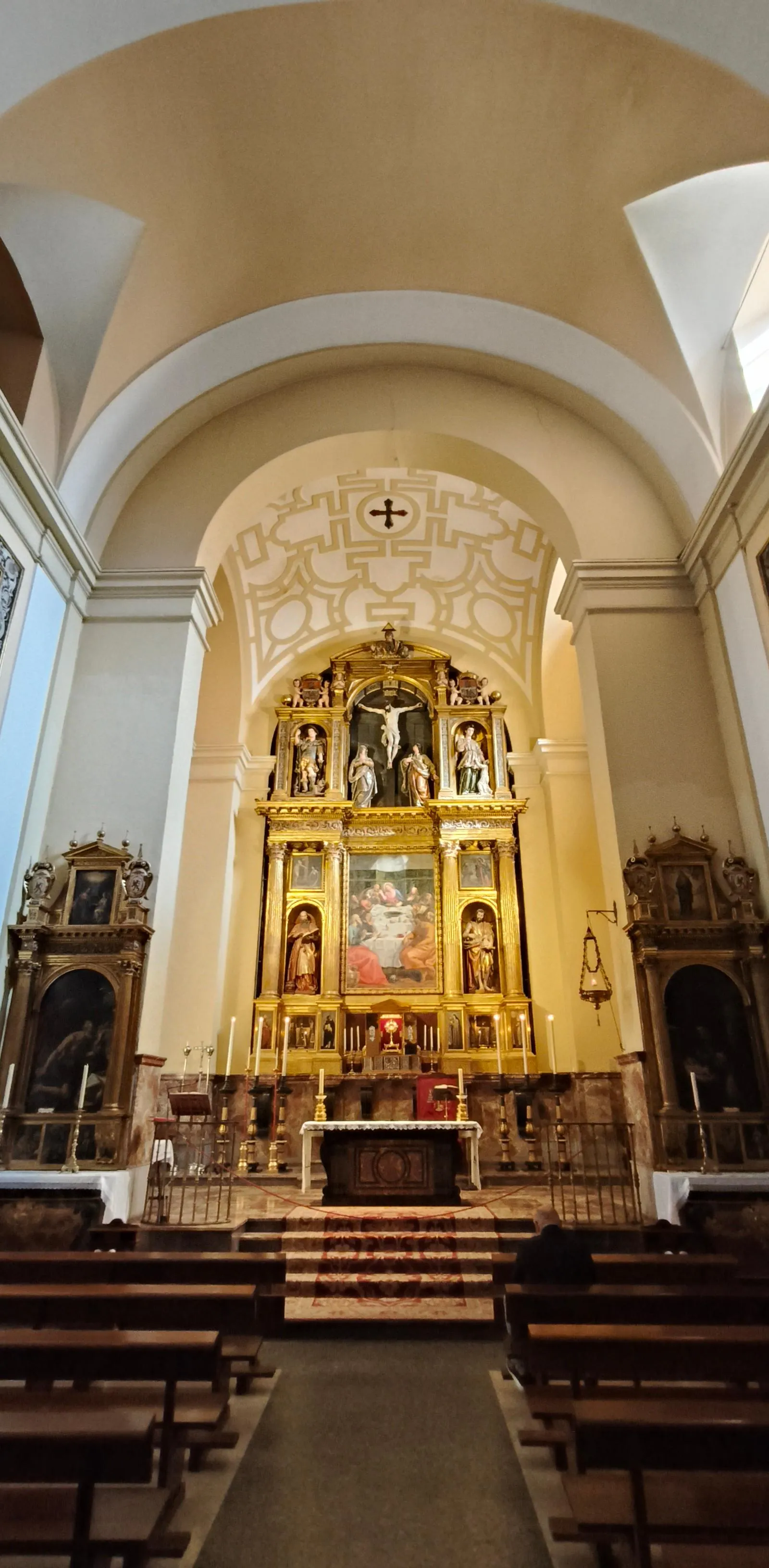 Elaborate gilded altarpiece in a historic Madrid church, featuring religious artworks under an arched ceiling.