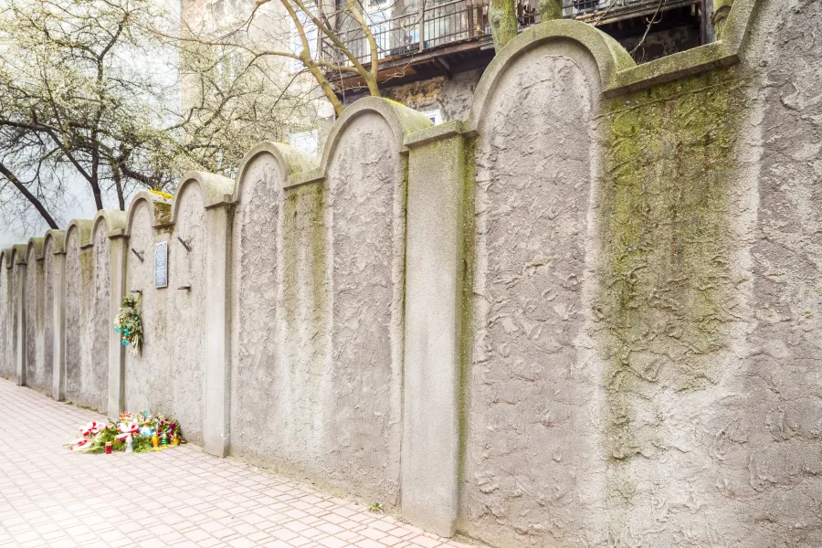 Remuh Cemetery wall in Krakow with flowers and candles.