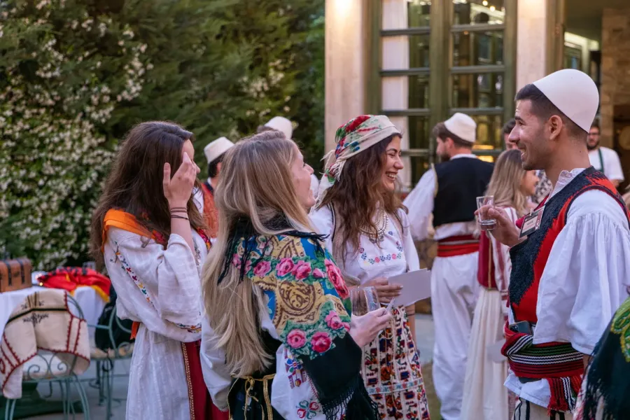 Tourists enjoying an Albanian Night show, interacting with performers in traditional clothing.