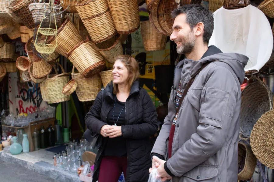 Happy couple on a guided tour in Athens, admiring traditional woven baskets.