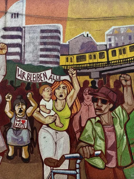A vibrant mural in Berlin depicting a protest scene with diverse people and a U-Bahn train.