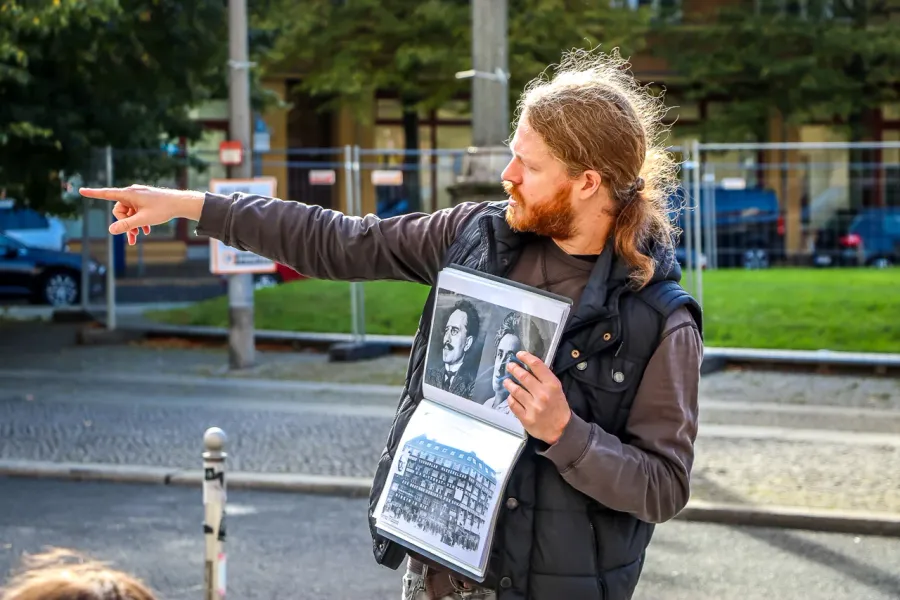 A tour guide in Berlin shows historical photos to a group.