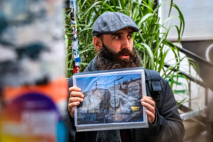 A tour guide in Berlin shows a photo of a vibrant street art mural.