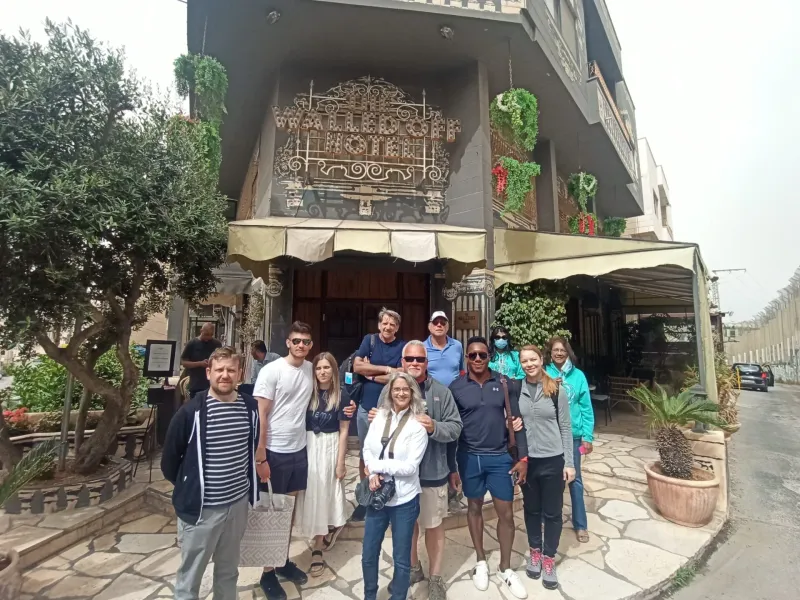 A happy tour group poses for a photo in front of The Walled Off Hotel in Bethlehem.