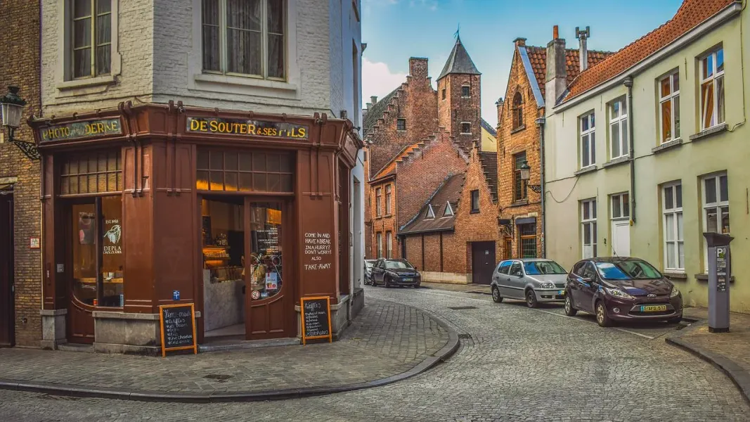 Charming cobblestone street in Bruges, Belgium, with historic buildings and a chocolate shop.
