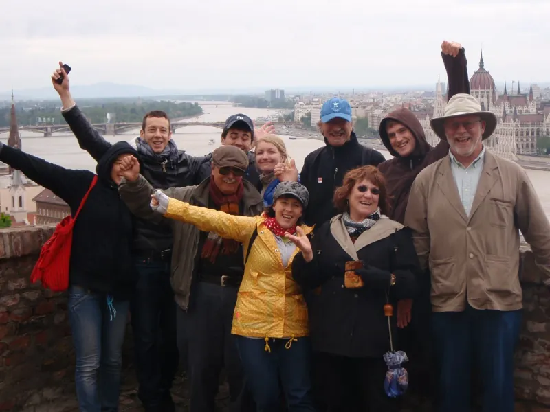 Happy tourists on a Budapest city tour, enjoying a panoramic view of the Parliament.