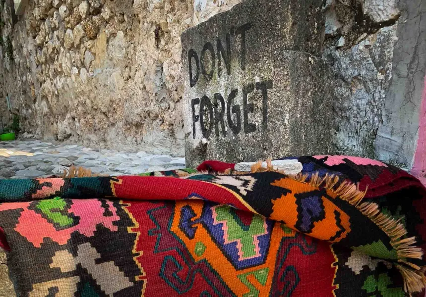 Colorful rug in Berat, Albania near a stone wall.